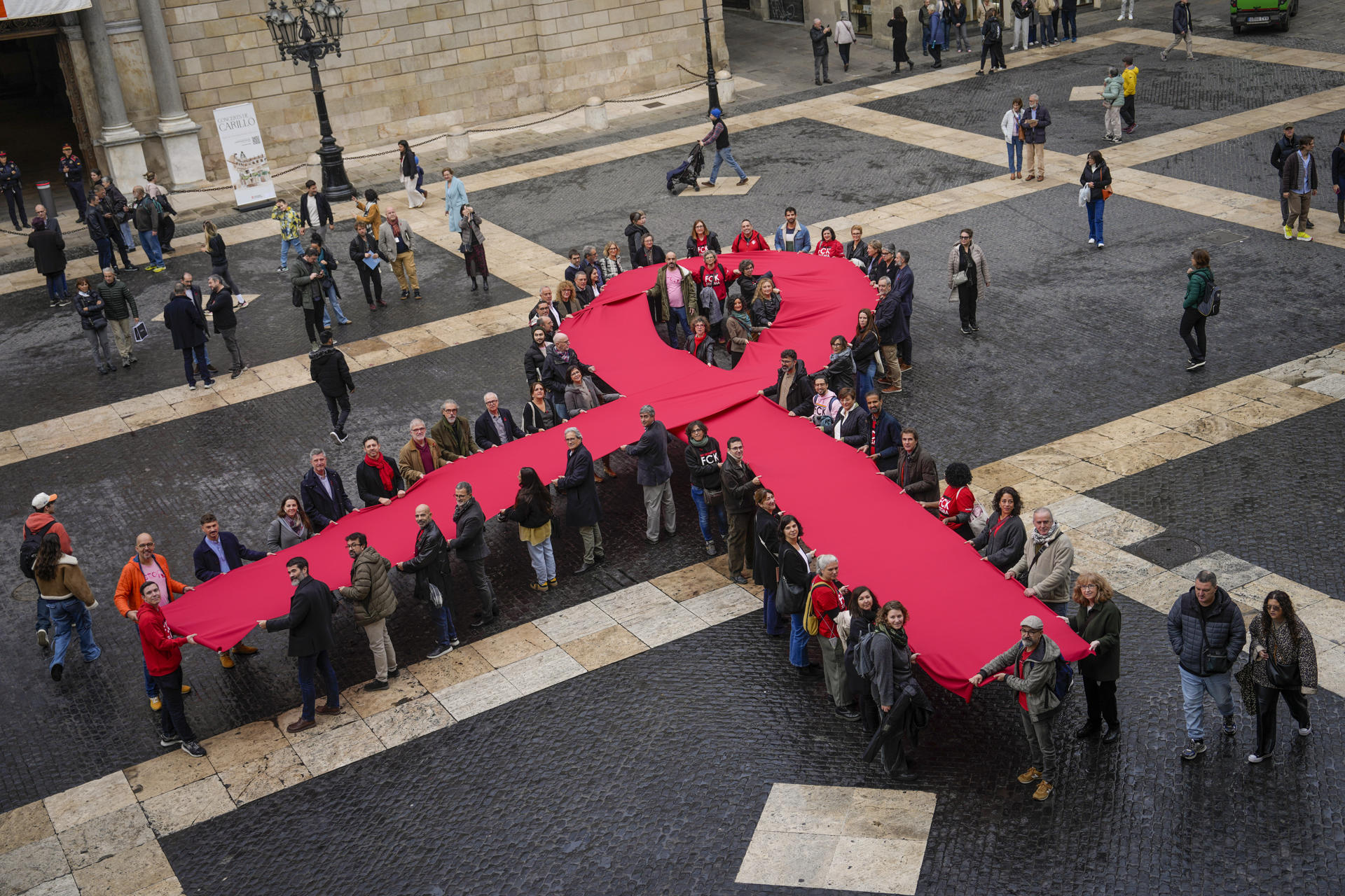 Un lazo memorial del sida se despliega en la plaza Sant Jaume. Barcelona, este domingo, en el que se celebra el Día Mundial del Sida. / Foto: EFE/Enric Fontcuberta.