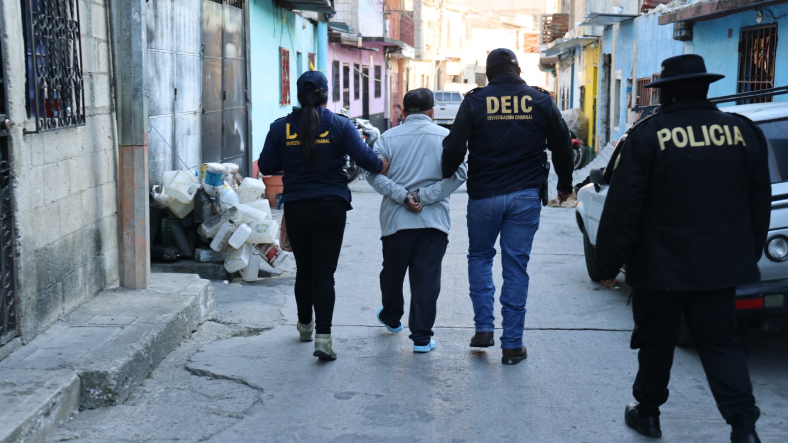 Agentes conducen a uno de los capturados por homicidio y homicidio en grado de tentativa.