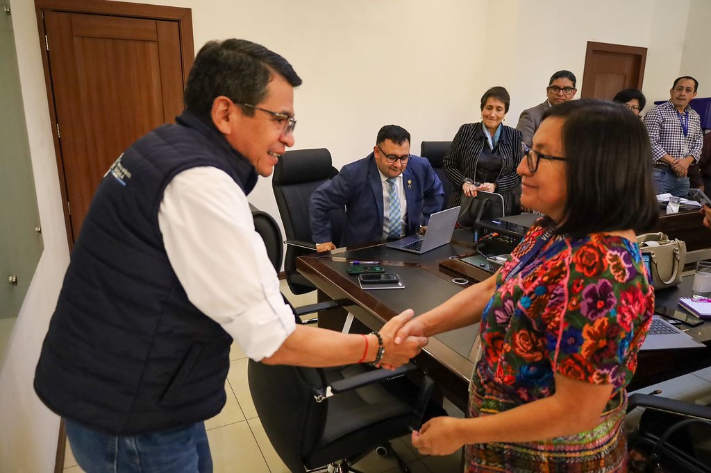 El titular del CIV, Miguel Ángel Bobadilla, saluda a la gobernadora de Chimaltenango, María del Tráncito Calán, en reunión sobre reparación de carreteras en ese departamento.