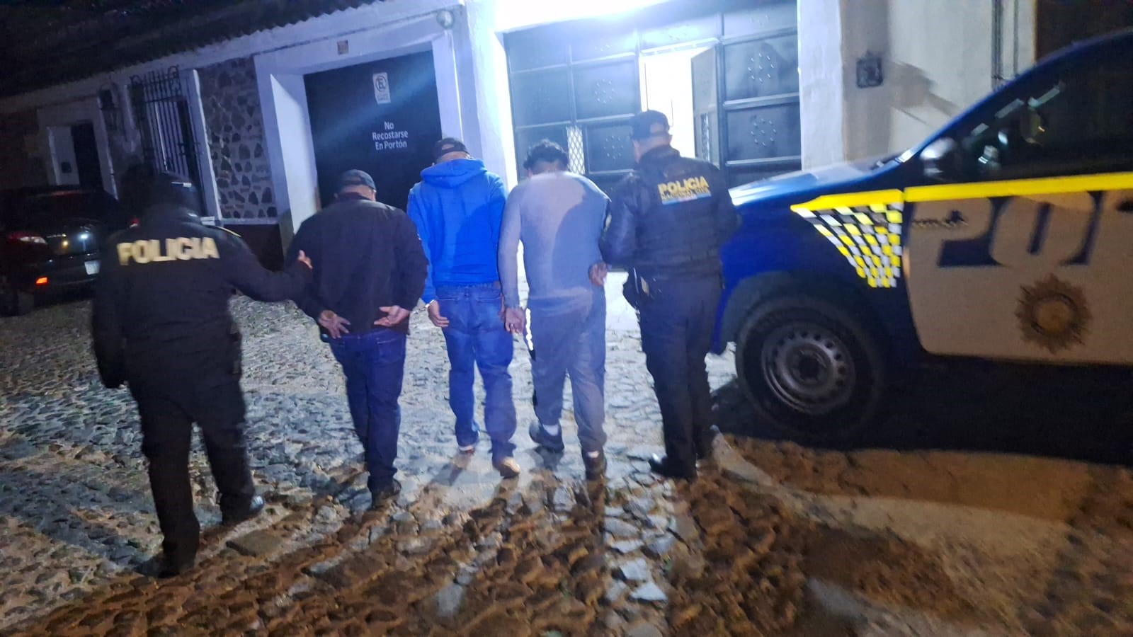 Agentes de la PNC conducen a detenidos por el robo de un cabezal con furgón cargado de maíz, frijol y aceite.