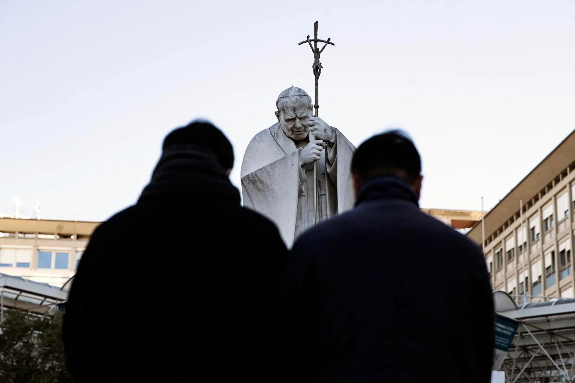 Feligreses continúan llegando a orar por la salud del papa Francisco frente un monumento a san Juan Pablo II frente al hospital Gemelli de Roma.