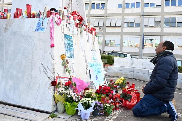 Un feligrés ora junto a un altar improvisado a los pies de un monumento al papa Juan Pablo II afuera del Hospital Policlínico Gemelli, donde Francisco cumple 19 días internado.