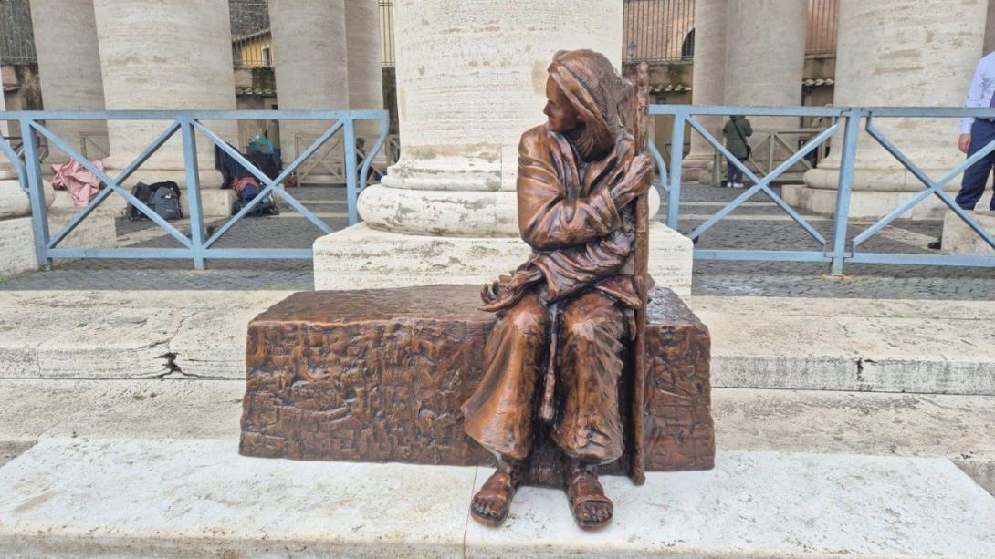 Vista de frente la nueva escultura en la Plaza de San Pedro representa a una persona sin hogar.