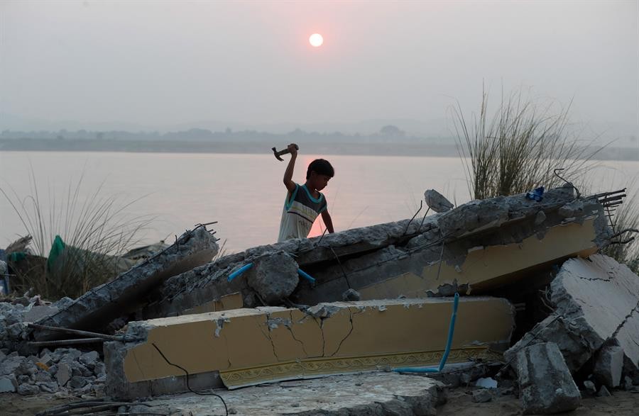 Un niño trata de liberar paso fluvial de escombros del terremoto en Birmania. / Foto: EFE.
