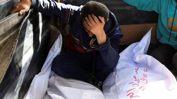 Un hombre llora junto a los cuerpos de familiares en Gaza.