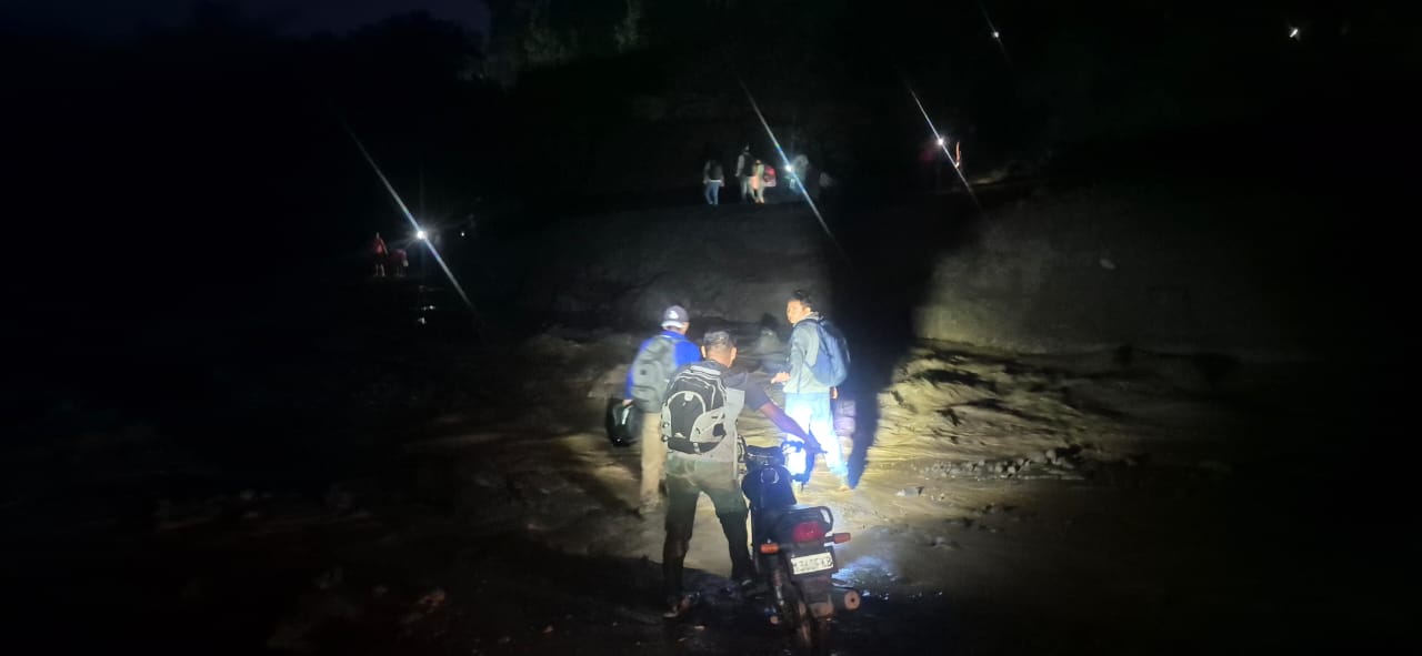 Personas atravesando el río El Jute, cuya corriente arrastra material arrojado por el volcán de Fuego, ramas, rocas y demás. / Foto: Conred.