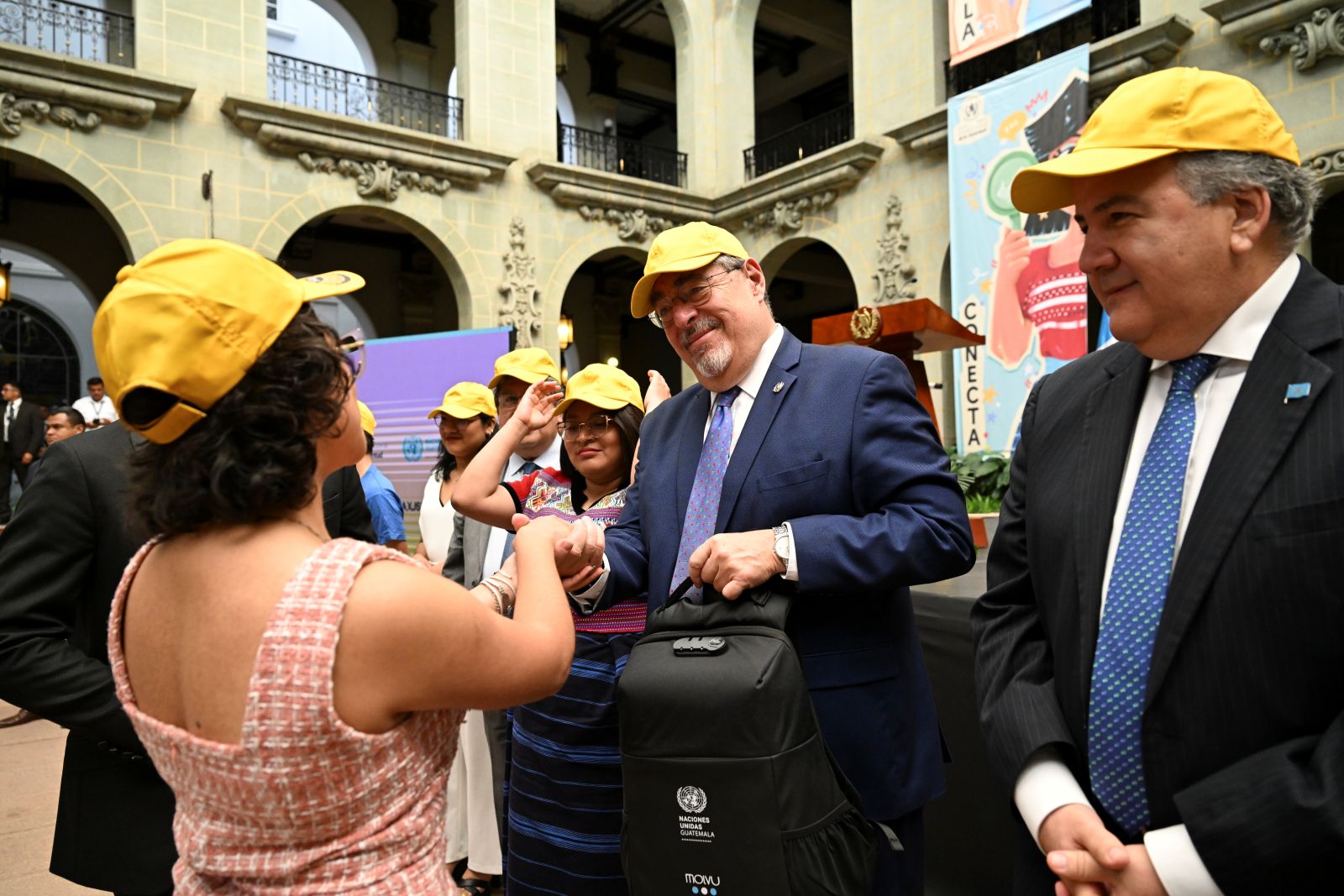 Jóvenes integrantes de la Red Juventud Chispuda entregan al presidente Bernardo Arévalo una gorra y una mochila.