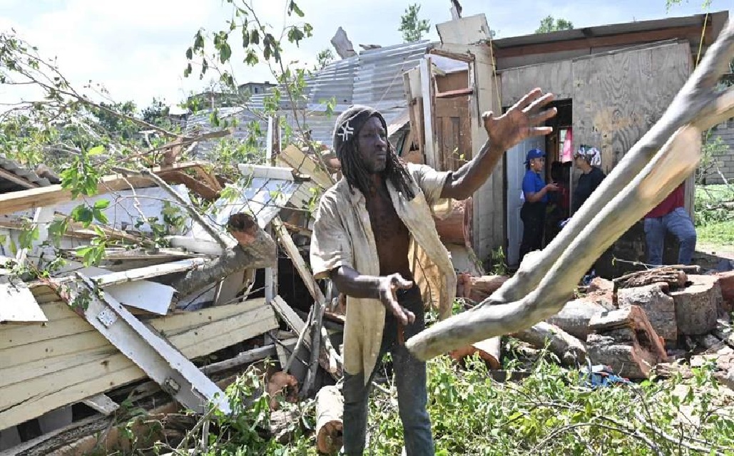 Un jamaicano trata de despejar lo que quedó de su vivienda que quedó destruida al caerle un árbol por el paso del huracán Melissa.