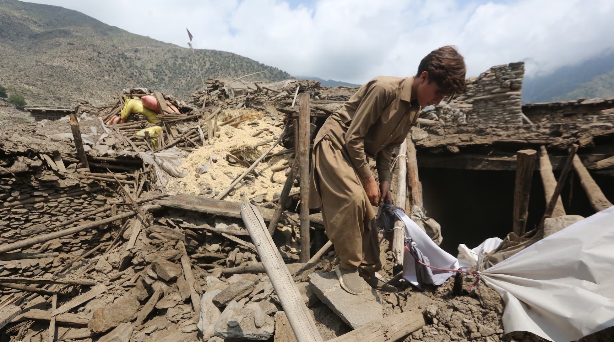 Un hombre algunas de sus pertenencias entre los escombros de su vivienda luego del terremoto en Afganistán.
