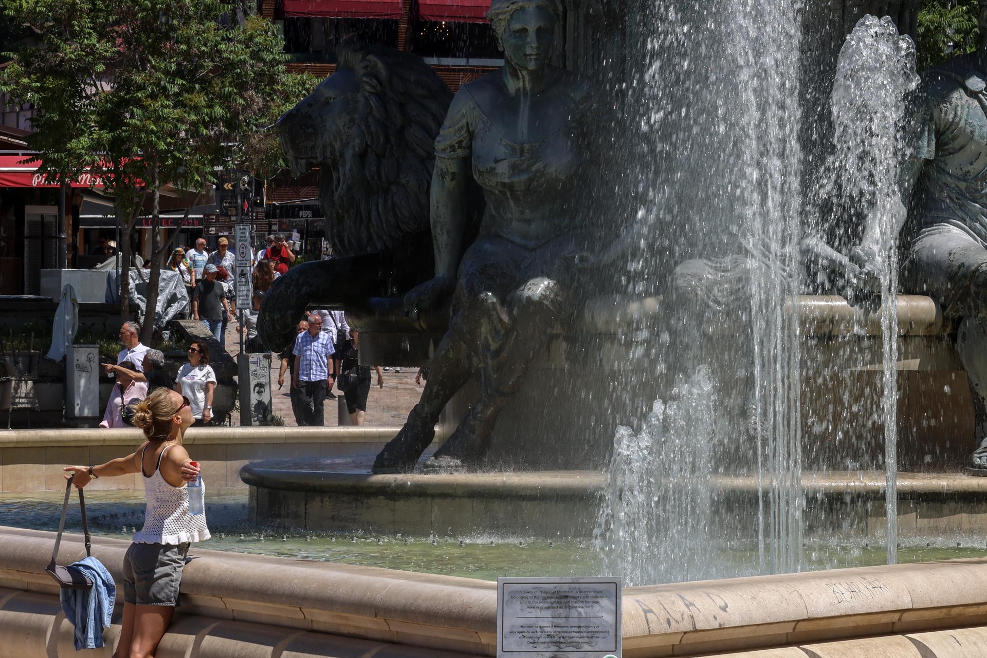 Una mujer se refresca en una fuente, en Macedonia del Norte, a causa del intenso calor que afecta gran parte de Europa.