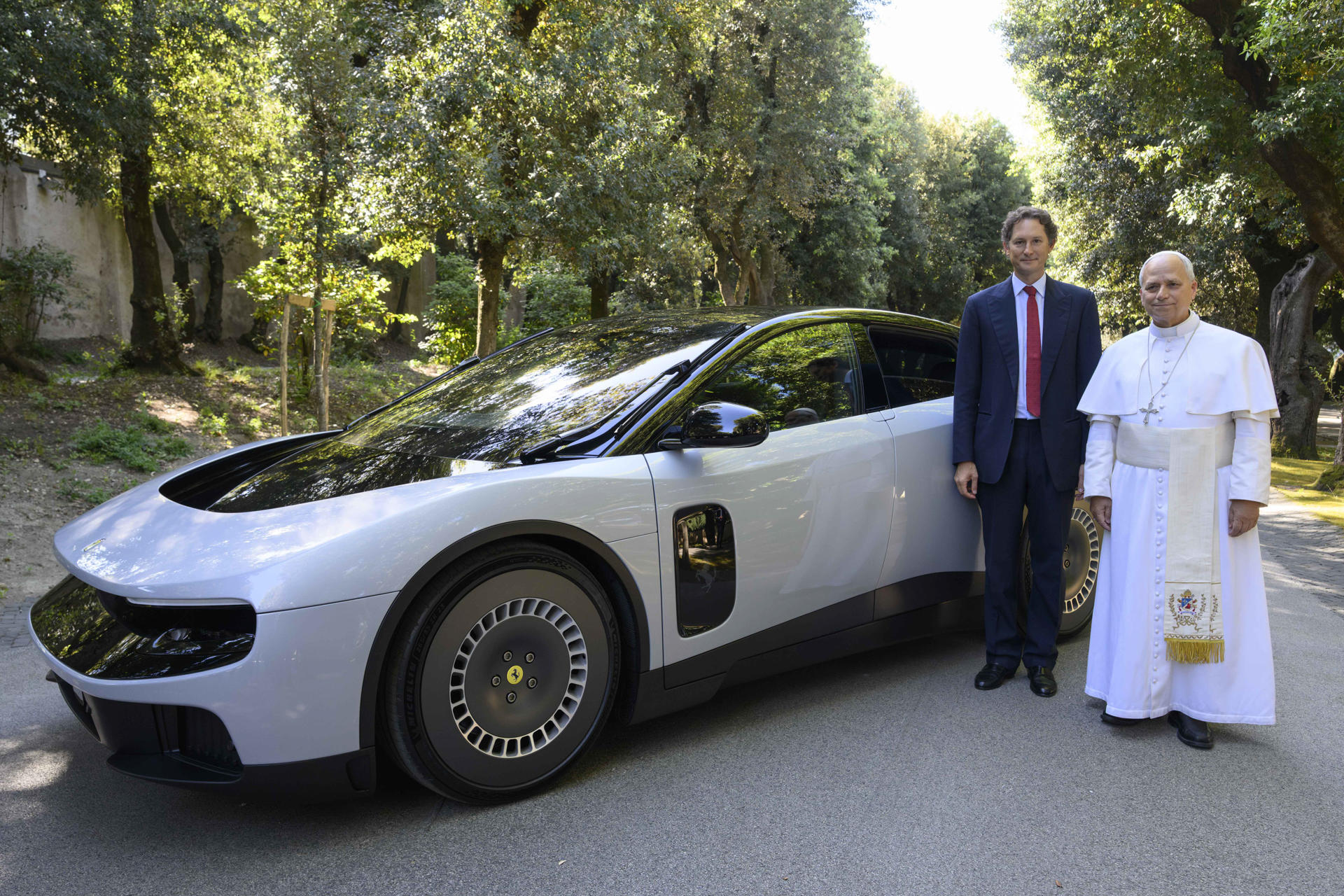 El papa León XIV y el presidente de Ferrari, junto al primer automóvil eléctrico de esa casa automotriz.
